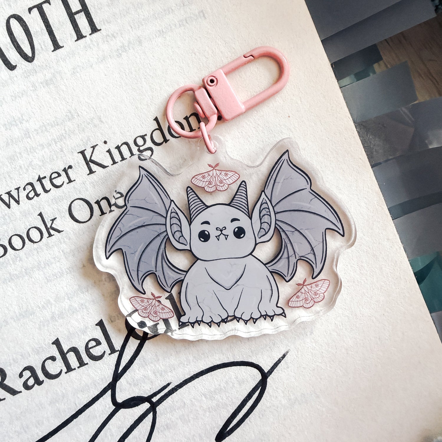 Keychain with a cute bat/gargoyle design on a book page